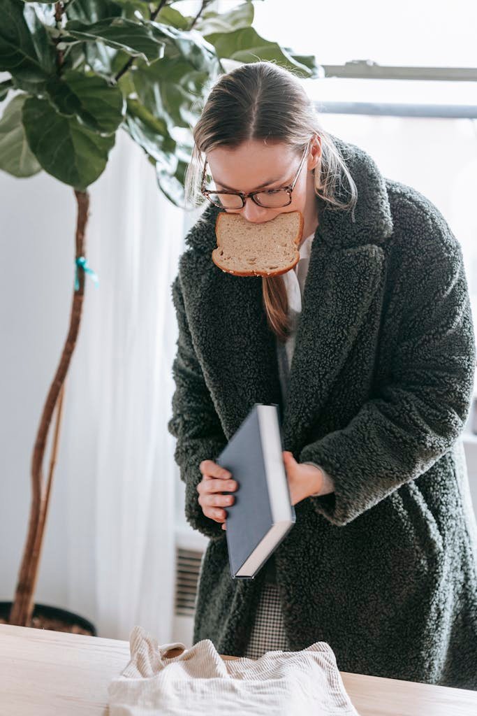 Woman with book and bread in warm clothes at home